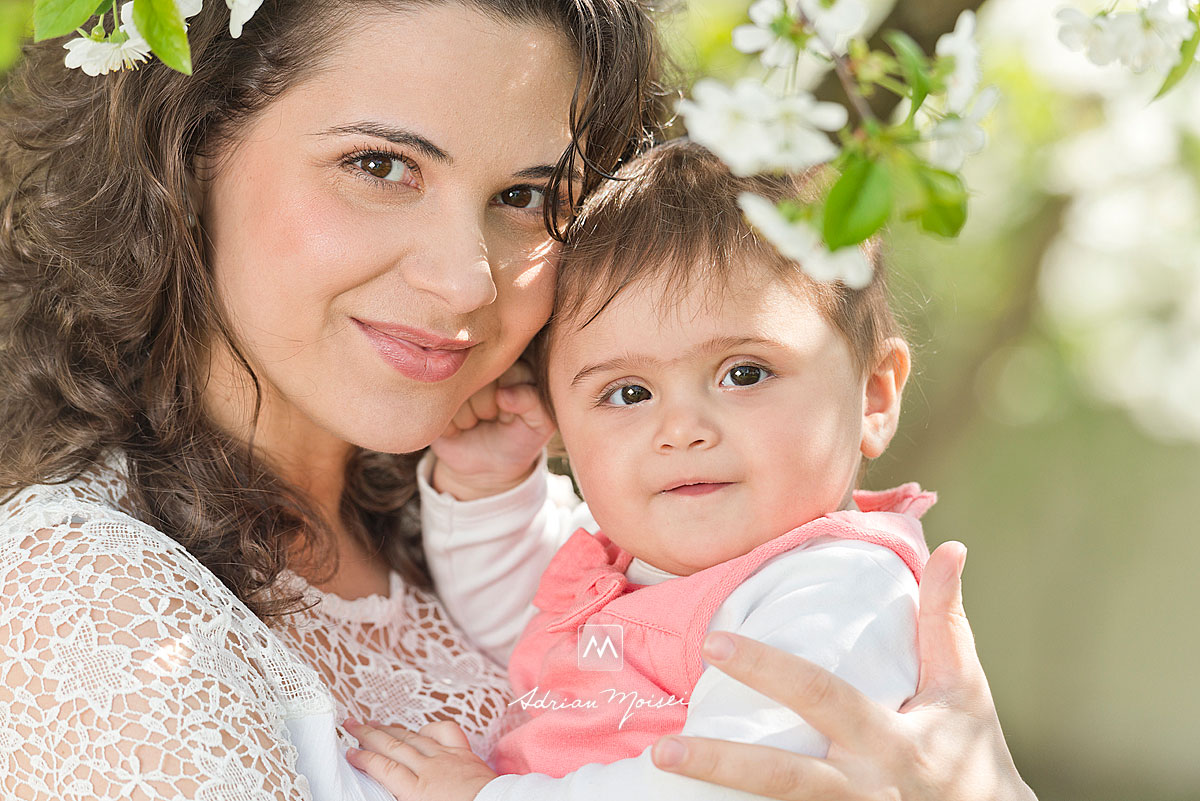 Bebelus in bratele mamei sale, intr-o livada inflorita