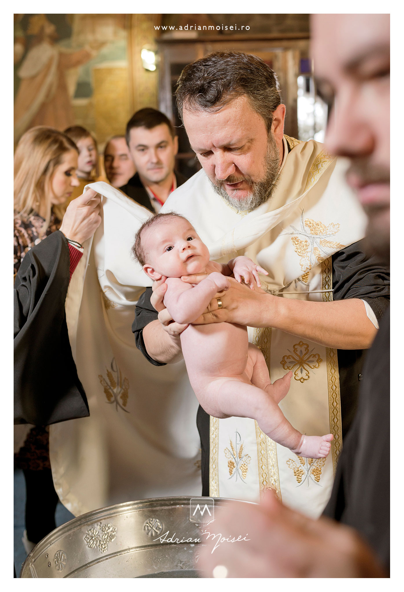 Preot cu un bebeluș în brațe pregătindu-se de botez la Iași, biserica Sfântul Nicolae Domnesc
